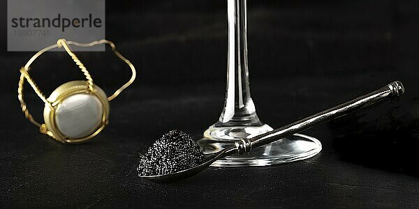 Schwarzer Kaviar  ein Glas Champagner und ein Sektkorken Panorama auf dunklem Hintergrund  selektiver Fokus