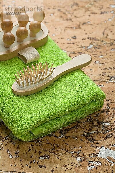 Massagegerät und Haarbürste auf grünem Handtuch