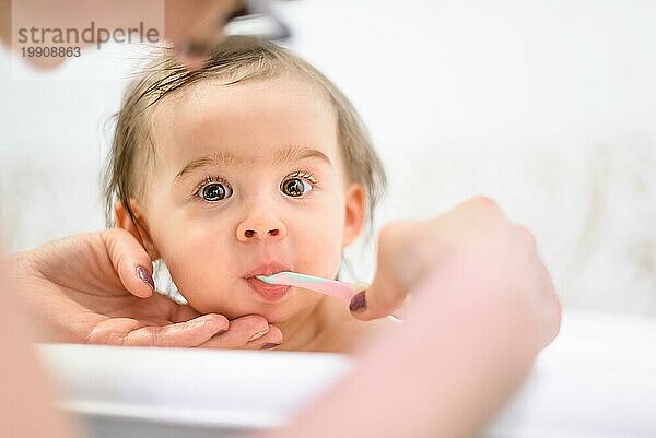 Happy 1 Jahr altes Baby in der Badewanne Zähneputzen im Bad mit Mutter. Hygienekonzept