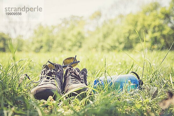 Schuhe und eine Flasche Wasser auf der grünen Wiese. Freie Zeit im Sommer