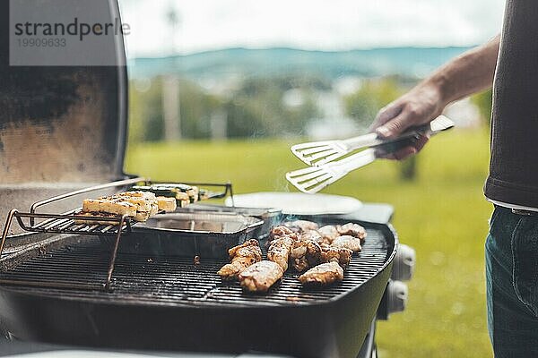 Nahaufnahme von Hähnchenflügeln  Käse und Gemüse auf dem Gasgrill. Sommerzeit  im Freien