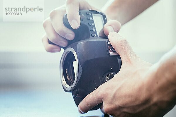 Die Hände eines Fotografen berühren eine professionelle Spiegelreflexkamera  offener Sensor