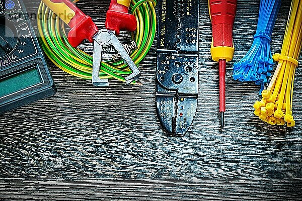 Elektrischer Tester Schraubenzieher gerollte Kabelbinder Abisolierzange auf Holzbrett
