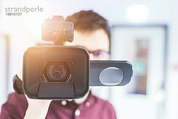 Männlicher Kameramann hält einen professionellen Video Camcorder  unscharfer Hintergrund