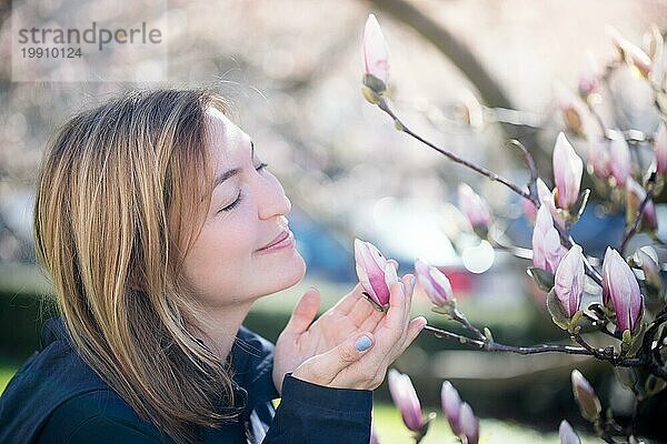 Schönes Mädchen riecht an Magnolienblüten im Frühling  Salzburg  Schönheit