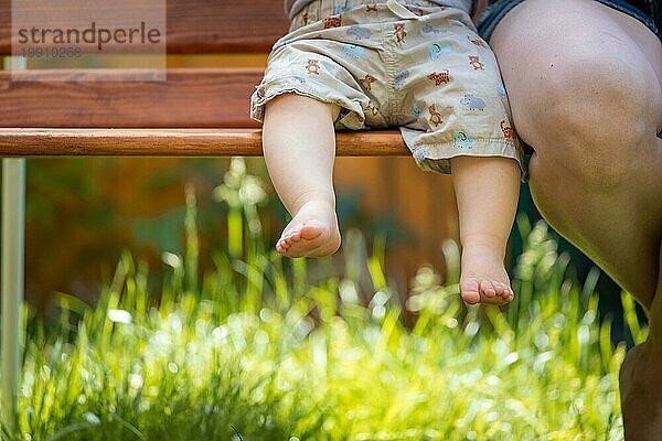 Baby aufwachsen Konzept: Close up von barfuß Baby Füße sitzen auf Parkbank  Sommerzeit