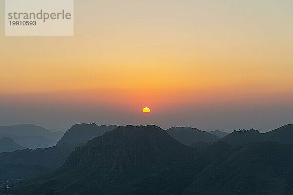 Silhouetten der kaukasischen Berge gegen die untergehende Sonne am klaren Himmel