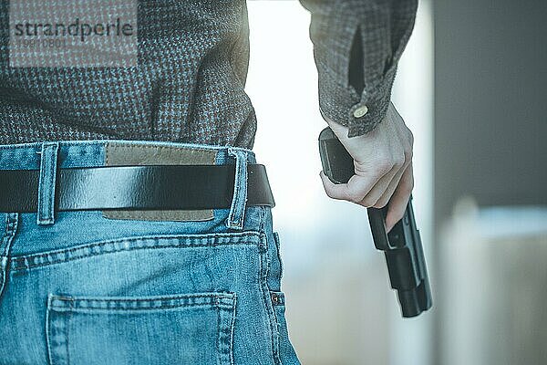 Ein Undercover Polizist hält eine schwarze Waffe in der Hand  bereit zum Schießen