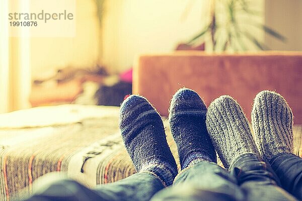 Füße mit Wollsocken in der Winterzeit: Pärchen entspannt auf der Couch