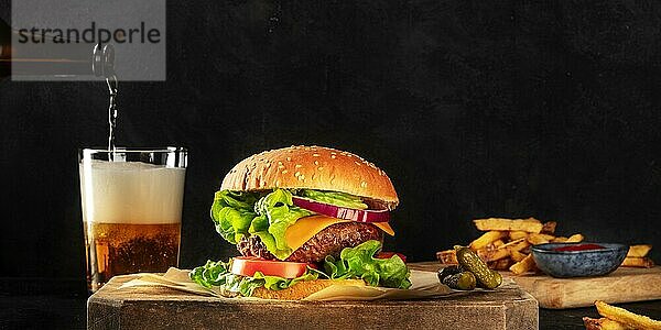 Burger und Bier Panorama. Hamburger mit Rindfleisch  Käse  Zwiebel  Tomate und grünem Salat  eine Seitenansicht auf einem dunklen Hintergrund mit Kopierraum. Selektiver Fokus