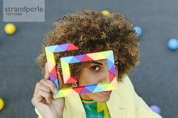 Woman with curly hair looking through colorful toy