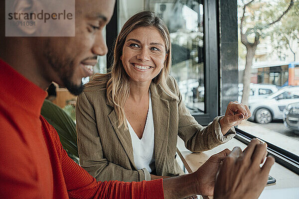 Happy businesswoman with colleague sitting at cafe