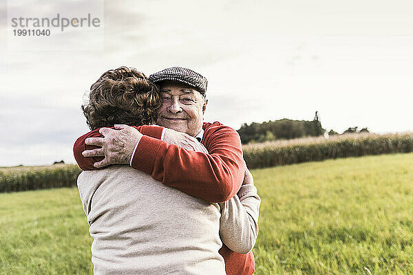 Lächelnder älterer Mann umarmt Frau auf dem Feld