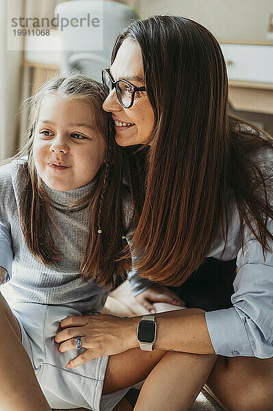 Liebevolle Mutter sitzt mit Tochter zu Hause