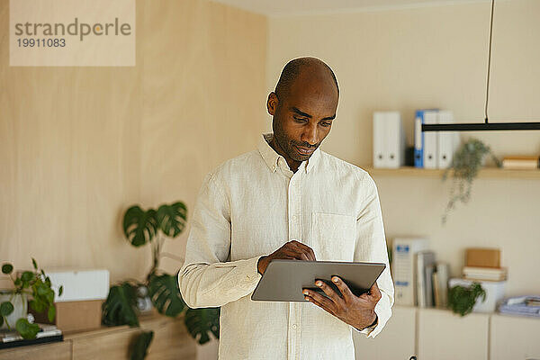 Selbstbewusster Geschäftsmann nutzt digitales Tablet im Heimbüro