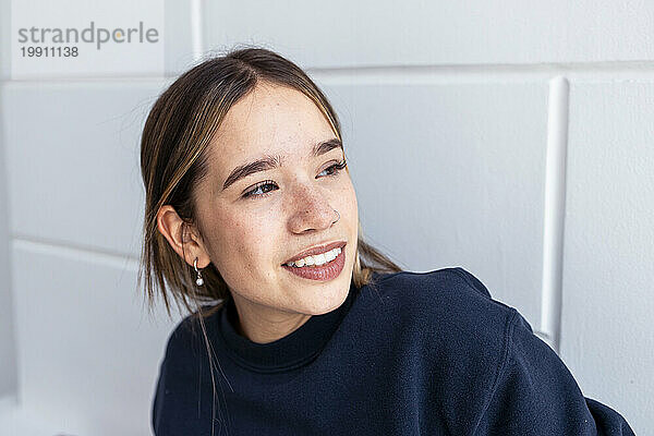 Lächelnde junge Frau vor der Wand