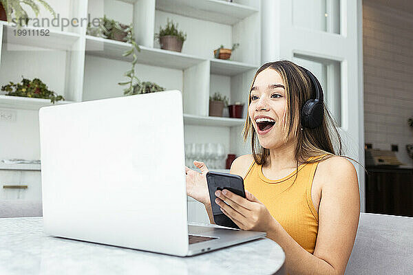 Überraschte Frau spricht zu Hause per Videoanruf über Laptop