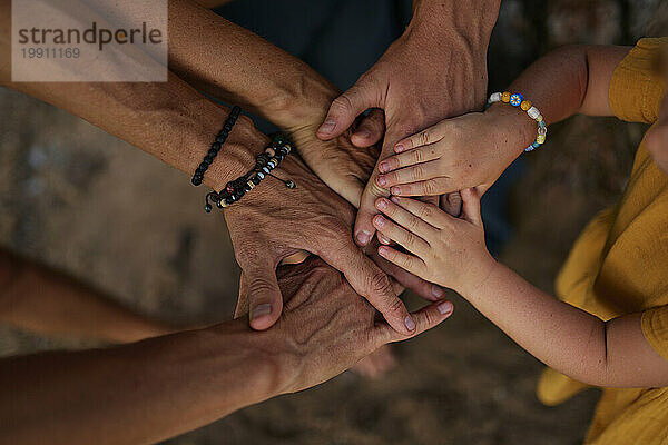 Family stacking hands together in park