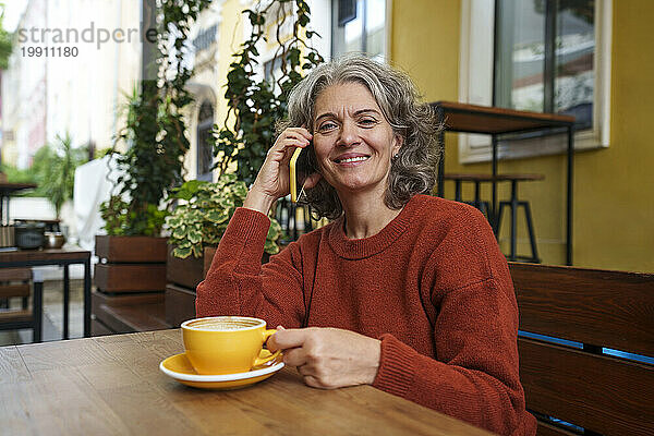 Lächelnde Frau telefoniert im Straßencafé