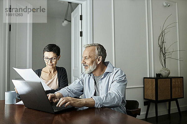 Ein Paar bespricht Geschäftspapiere und sitzt vor einem Laptop