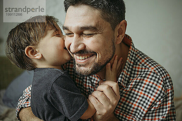 Glücklicher Vater umarmt süßen Sohn zu Hause
