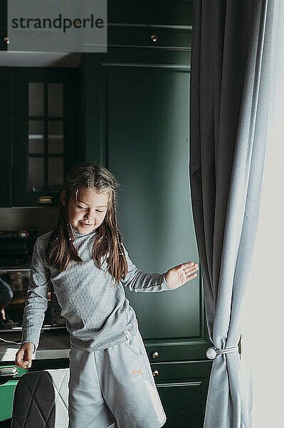 Smiling girl dancing in kitchen at home
