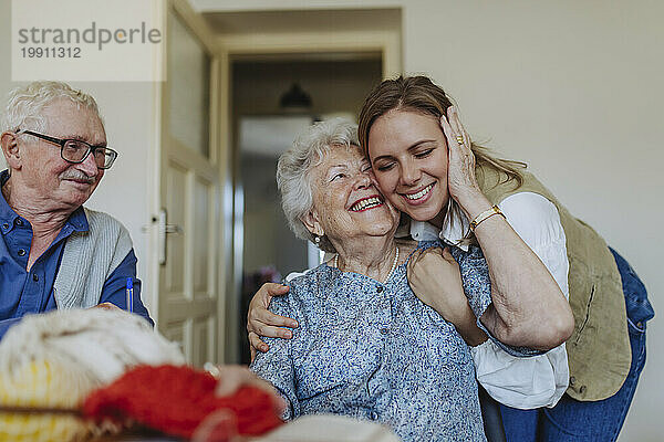 Glückliche ältere Frau umarmt die medizinische Fachkraft zu Hause