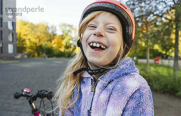 Fröhliches Mädchen  das mit Helm im Park lacht