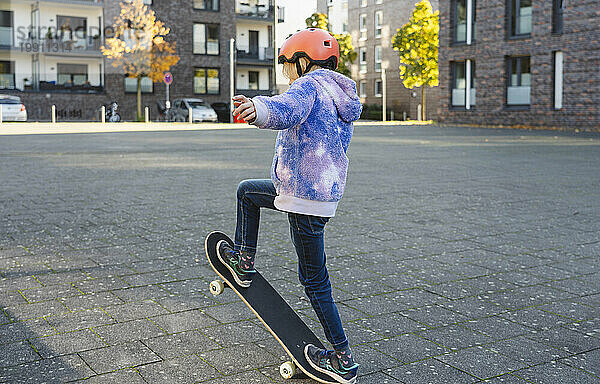 Mädchen mit Helm macht Ollie auf Skateboard