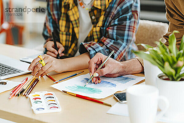 Illustrators making design on paper at desk in office