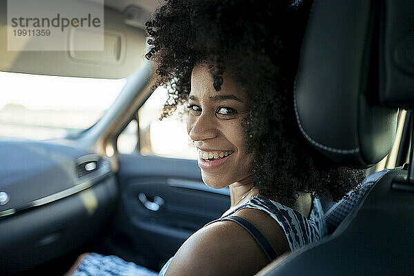 Happy woman looking over shoulder sitting in car