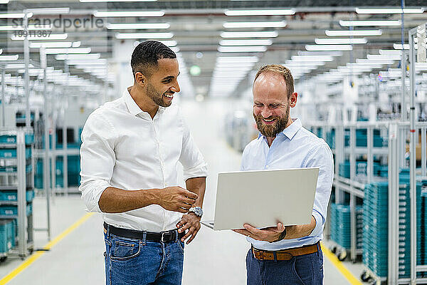 Zwei Geschäftsleute mit Laptop bei einem Treffen in einer Fabrik