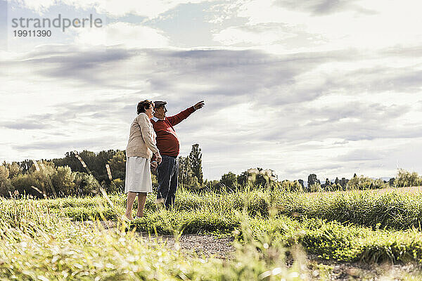 Älterer Mann gestikuliert mit Frau  die an einem sonnigen Tag auf dem Feld steht