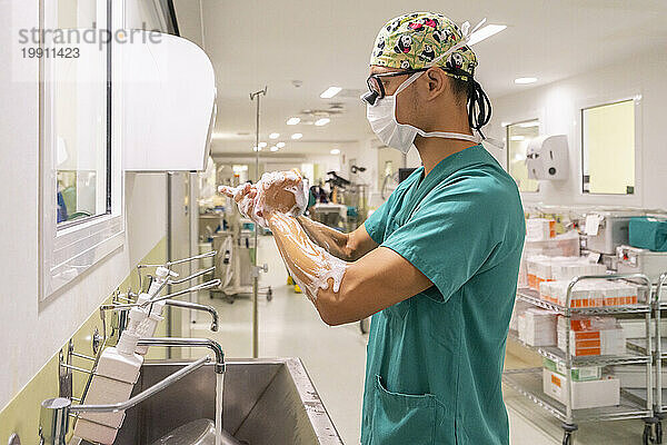 Chirurg mit Maske wäscht sich im Krankenhaus die Hände