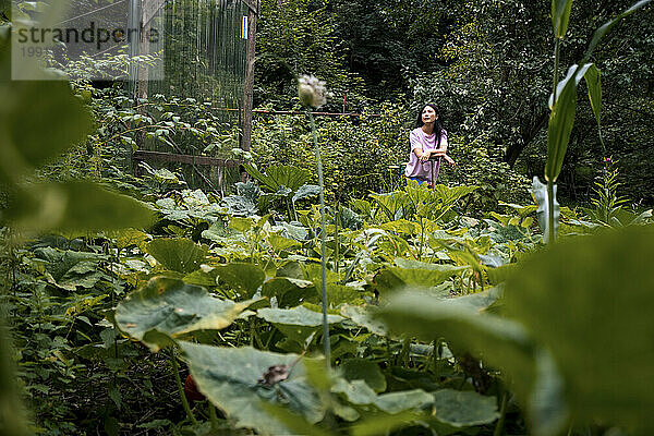 Thoughtful woman standing amidst plants