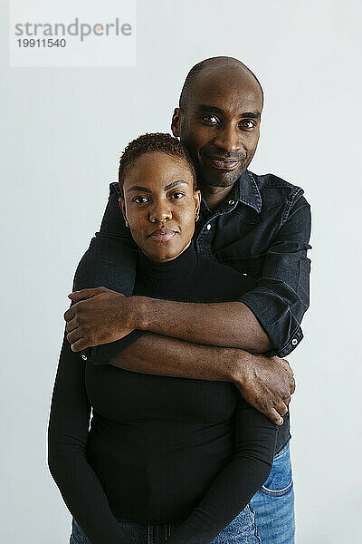 Smiling man embracing woman against white background