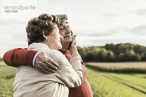 Glückliches älteres Paar verbringt seine Freizeit und umarmt sich auf dem Feld