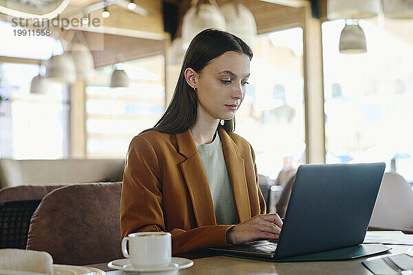 Geschäftsfrau trägt Blazer und arbeitet im Restaurant am Laptop