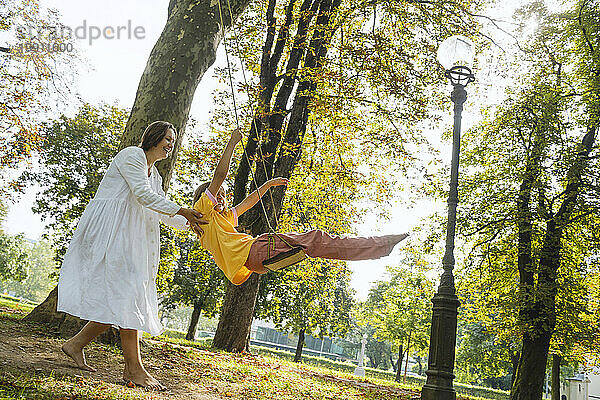 Mutter schwingt Tochter im Park