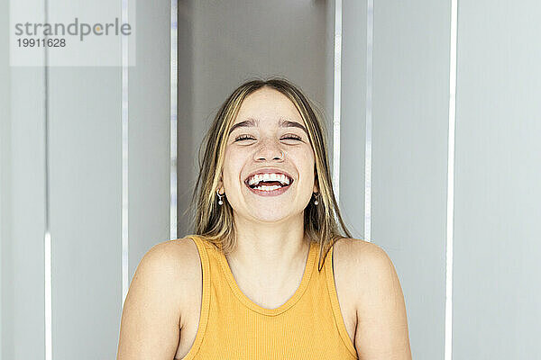 Cheerful woman with eyes closed laughing at home