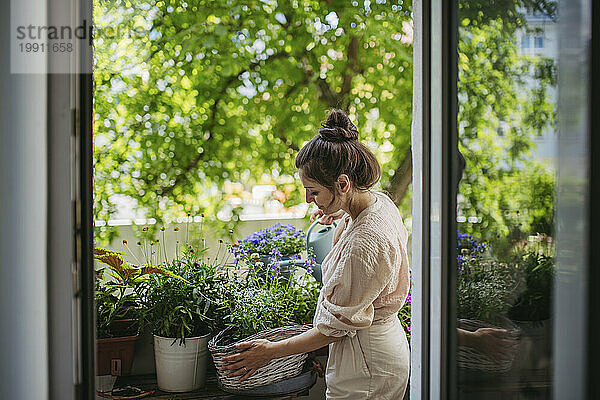 Frau gießt Blumen und kümmert sich um Pflanzen auf dem Balkon