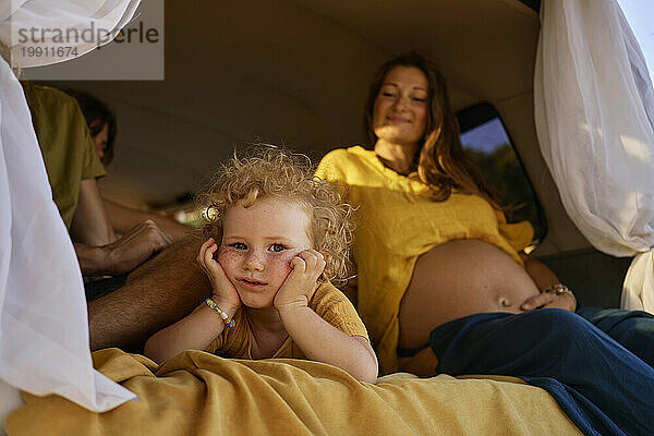 Nettes Mädchen liegt neben schwangerer Mutter im Wohnwagen