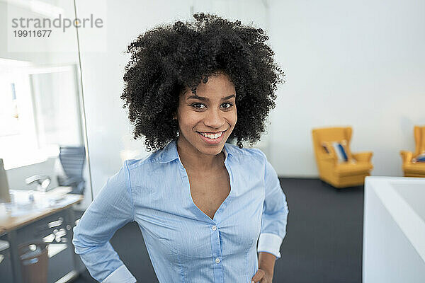 Lächelnde Geschäftsfrau mit lockigem Haar am Arbeitsplatz