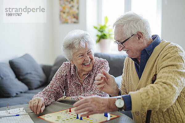 Glückliches älteres Paar  das zu Hause Ludo-Brettspiel spielt