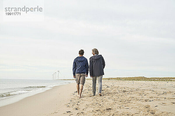 Vater und Sohn gehen gemeinsam am Strand spazieren