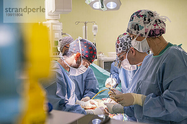 Ein Team von Chirurgen mit Masken führt eine Operation am Patienten in der Notaufnahme durch