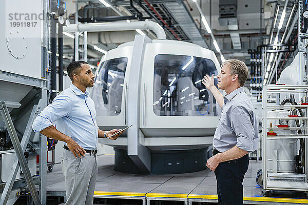 Zwei Geschäftsleute treffen sich an einer modernen Maschine in einer Fabrik