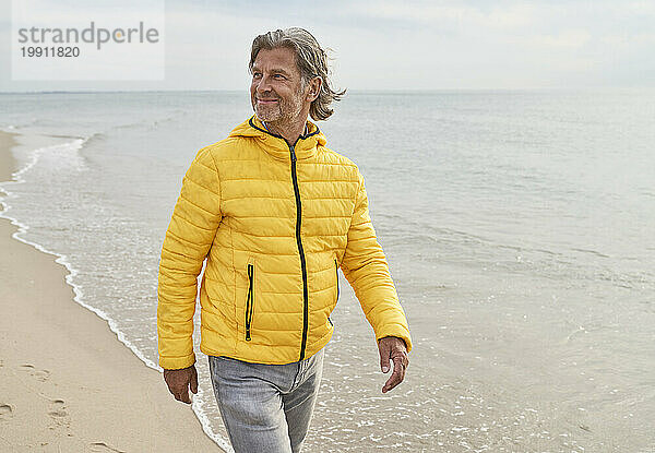 Glücklicher älterer Mann  der am Strand spaziert