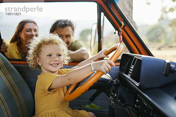 Lächelndes süßes Mädchen  das im Urlaub von den Eltern im Wohnwagen spielt