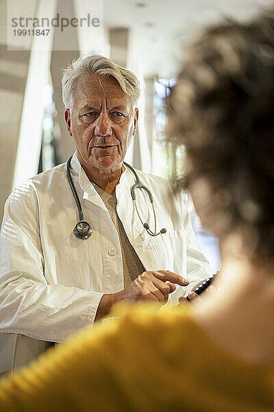 Leitender Arzt diskutiert mit junger Frau im Krankenhaus